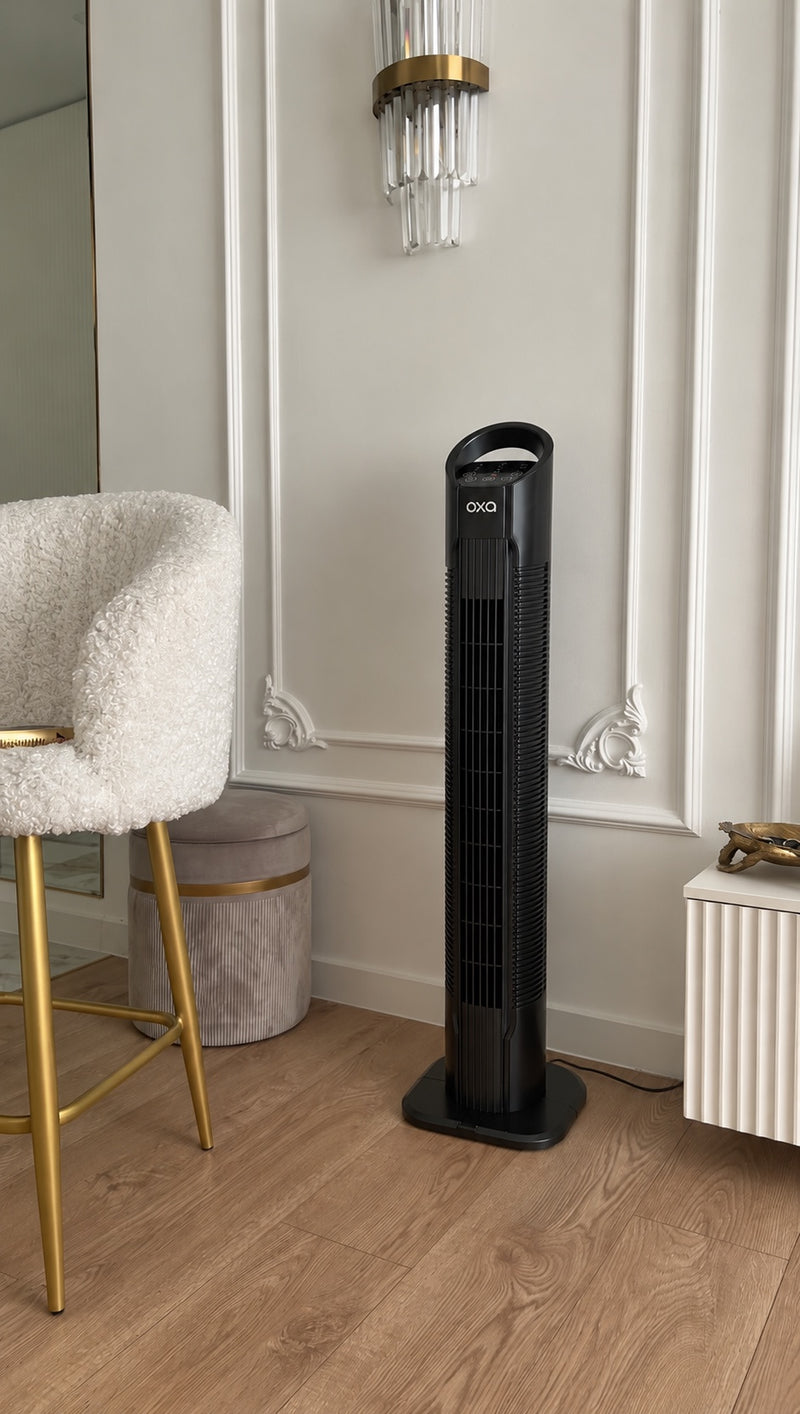 Oxa Tower Fan beside a chair in a bright room
